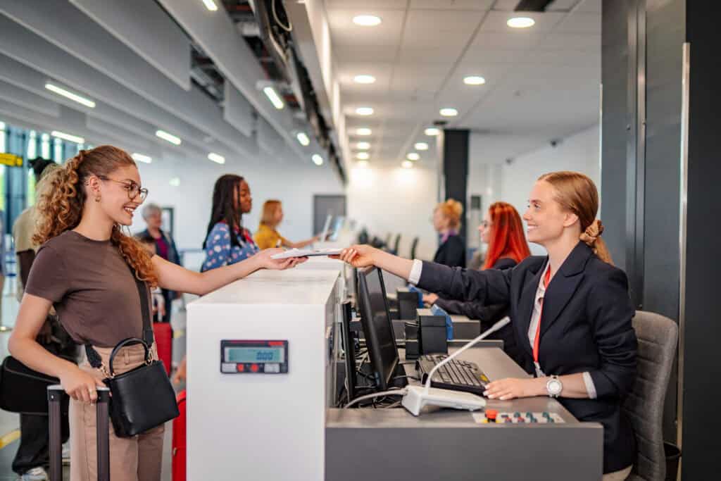 smiling airline agent checking passport of female 2026 10 14 21 58 02 utc